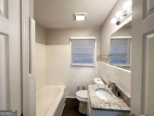 bathroom featuring a washtub, tile walls, vanity, wood-type flooring, and toilet