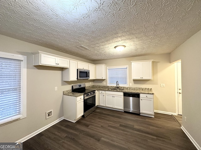 kitchen with stainless steel appliances, dark stone counters, and white cabinets