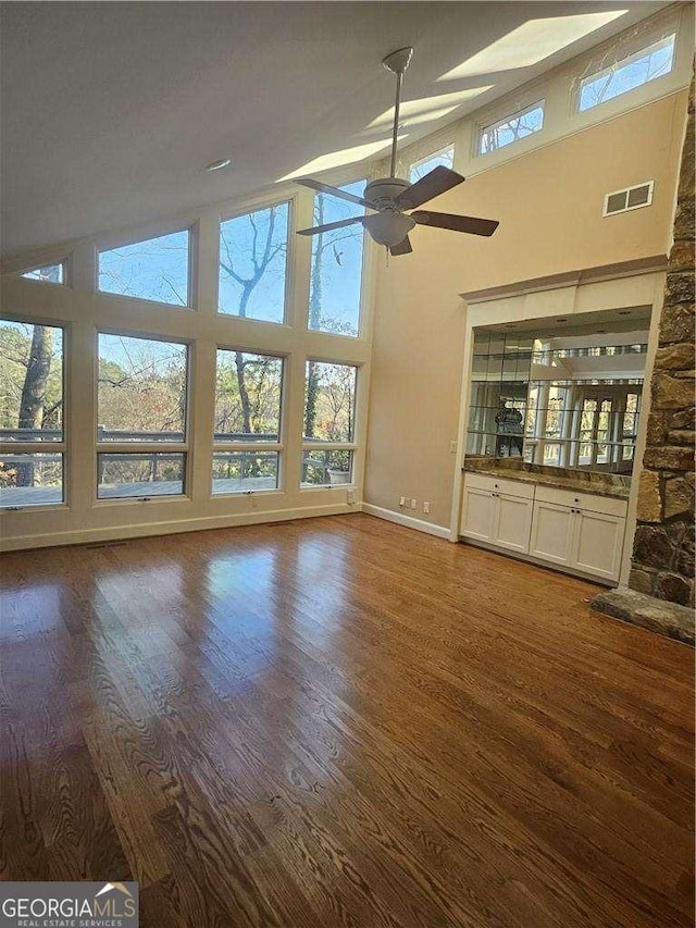 unfurnished living room featuring ceiling fan, dark wood-type flooring, and high vaulted ceiling