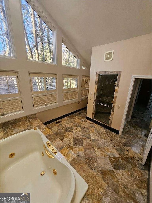 bathroom with lofted ceiling and a tub to relax in