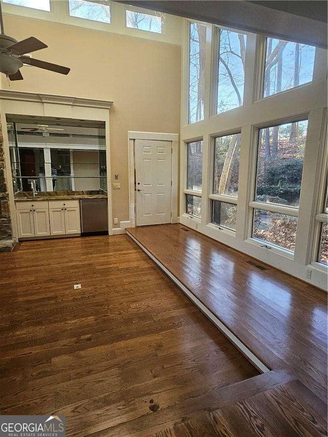 foyer entrance featuring ceiling fan, dark wood-type flooring, a healthy amount of sunlight, and a high ceiling