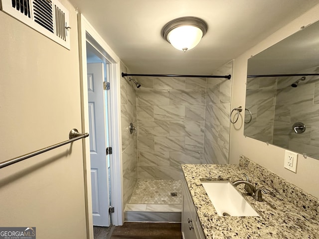 bathroom with tiled shower and vanity