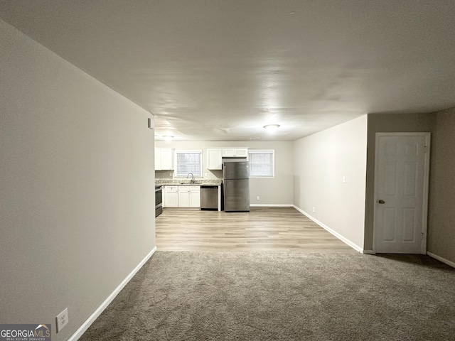 unfurnished living room with sink and light colored carpet