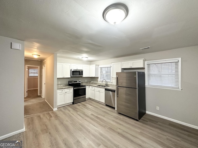 kitchen with white cabinetry, appliances with stainless steel finishes, sink, and light hardwood / wood-style floors