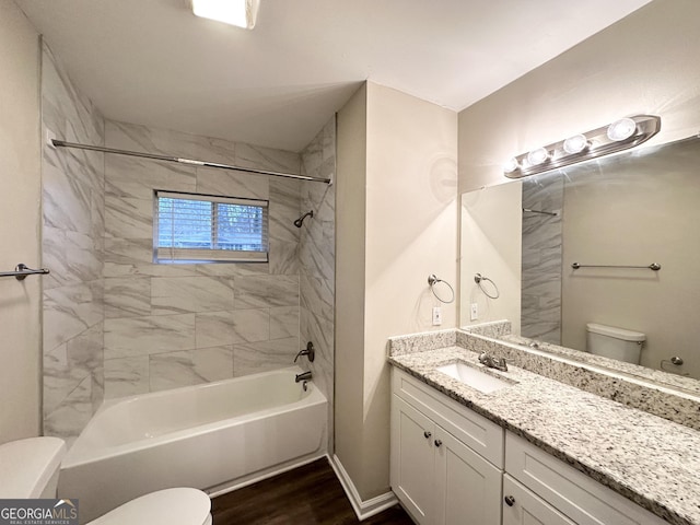 full bathroom with tiled shower / bath, wood-type flooring, vanity, and toilet