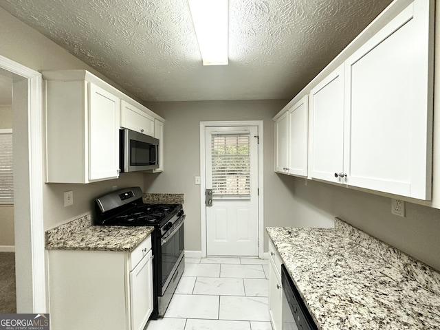 kitchen with white cabinetry, light stone counters, a textured ceiling, and appliances with stainless steel finishes