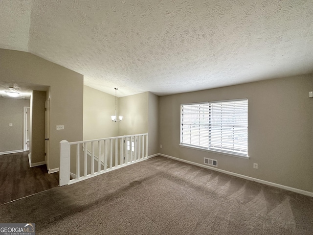 unfurnished room with lofted ceiling, a textured ceiling, an inviting chandelier, and dark colored carpet