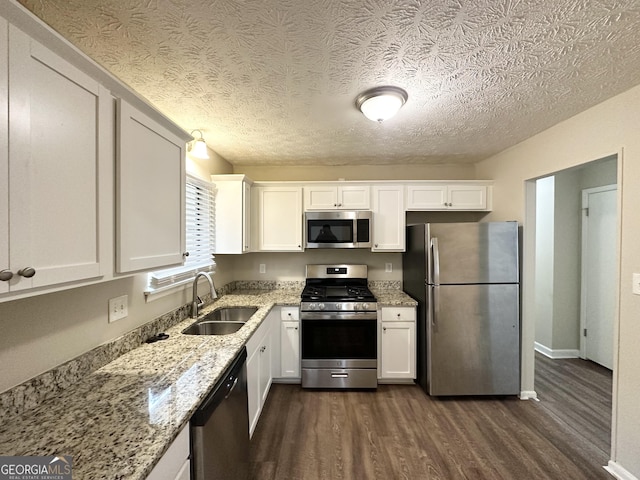 4305 Old Lake Dr, Decatur, GA 30034 - kitchen featuring appliances with stainless steel finishes, dark wood-style floors, white cabinetry, light stone counters, and a textured ceiling
