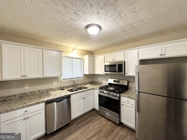 kitchen featuring dark hardwood / wood-style floors, white cabinetry, sink, light stone counters, and stainless steel appliances