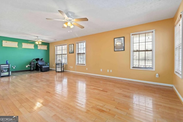 interior space featuring ceiling fan, a textured ceiling, and light hardwood / wood-style flooring