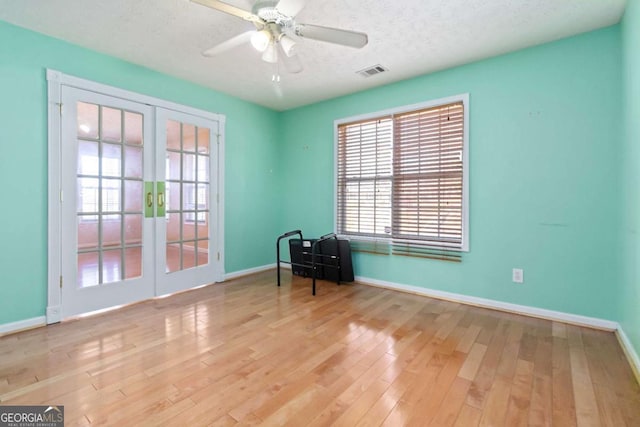 unfurnished room featuring french doors, ceiling fan, a textured ceiling, and light wood-type flooring