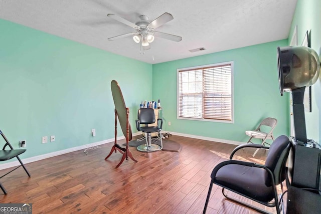 living area featuring dark hardwood / wood-style flooring, a textured ceiling, and ceiling fan