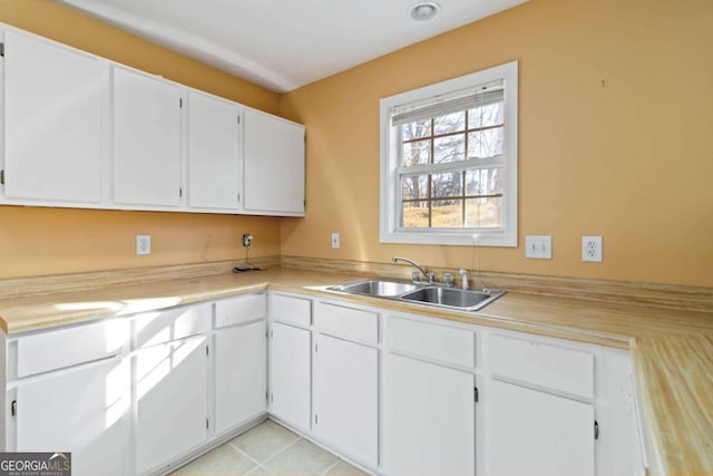 kitchen featuring light tile patterned flooring, sink, and white cabinets