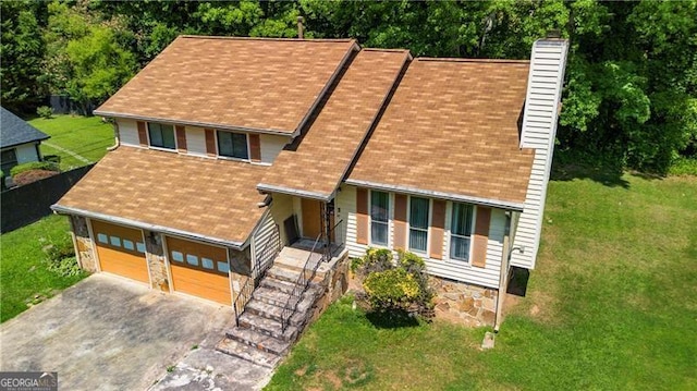 view of front facade with aphalt driveway, roof with shingles, a chimney, an attached garage, and a front lawn