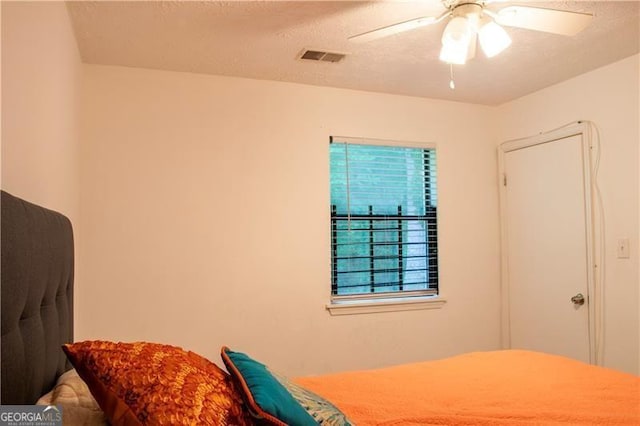 bedroom featuring a textured ceiling, visible vents, and a ceiling fan