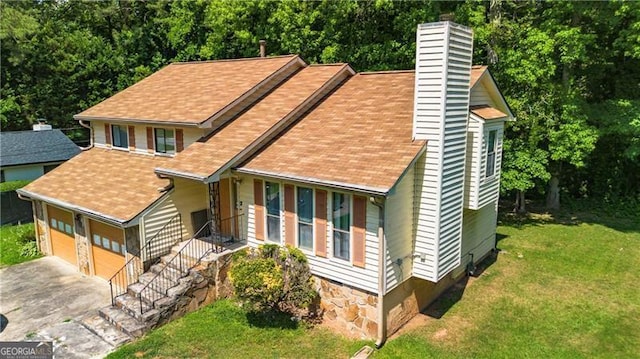 view of front of house featuring a garage, a chimney, a porch, aphalt driveway, and a front lawn