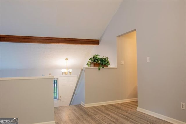 stairs featuring an inviting chandelier, wood-type flooring, and vaulted ceiling with beams