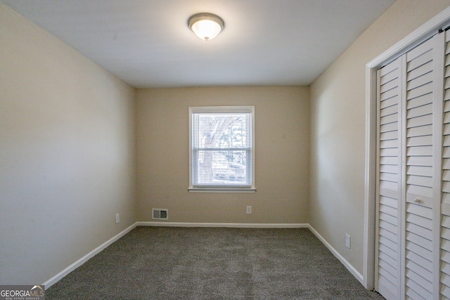 spare room featuring dark carpet