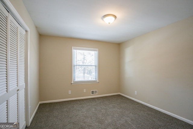 unfurnished bedroom with dark carpet and a closet