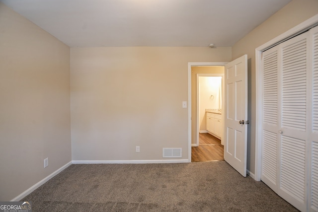 unfurnished bedroom with light carpet and a closet