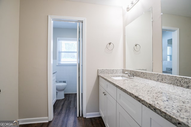 bathroom featuring vanity, toilet, hardwood / wood-style floors, and tile walls