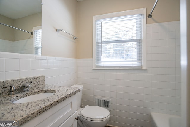 bathroom featuring tile walls, vanity, and toilet