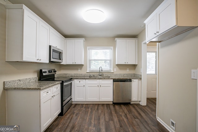 kitchen featuring sink, appliances with stainless steel finishes, plenty of natural light, light stone countertops, and white cabinets