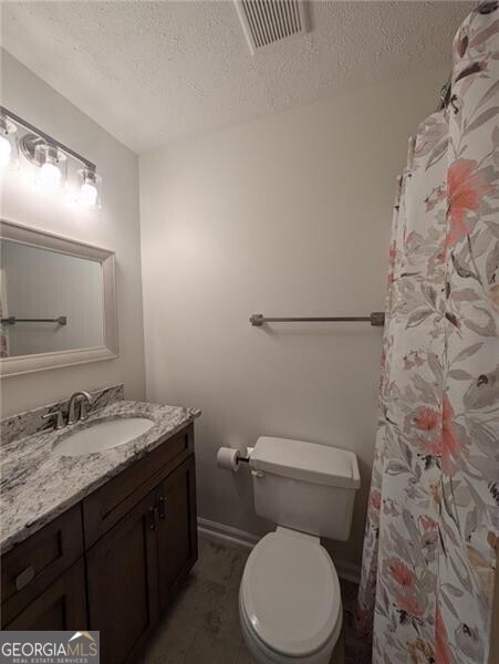 bathroom with vanity, toilet, and a textured ceiling