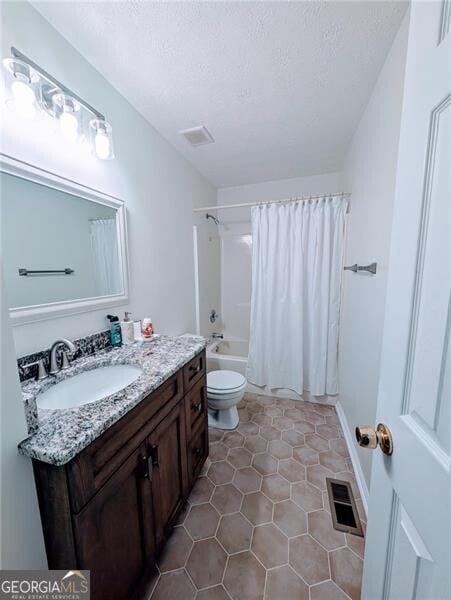 full bathroom with vanity, toilet, shower / bathtub combination with curtain, tile patterned floors, and a textured ceiling