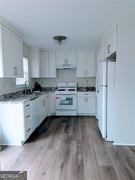 kitchen featuring sink, light hardwood / wood-style flooring, white appliances, light stone countertops, and white cabinets