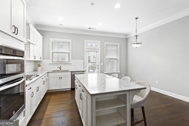 kitchen with white cabinetry, crown molding, light stone counters, a kitchen island, and pendant lighting