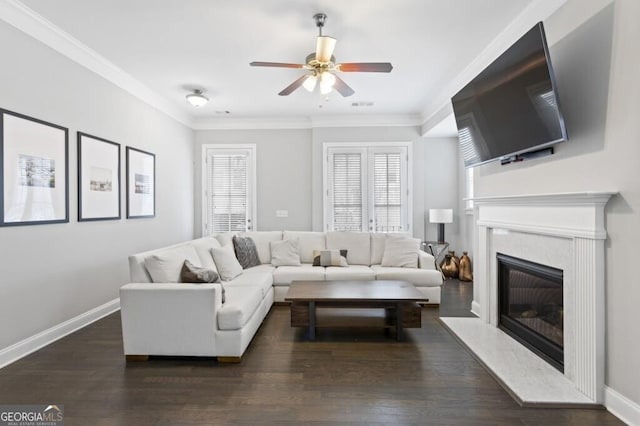 living room featuring dark wood-type flooring, ceiling fan, a premium fireplace, and crown molding