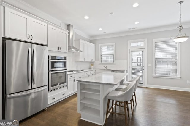 kitchen with a kitchen island, white cabinetry, appliances with stainless steel finishes, and wall chimney range hood