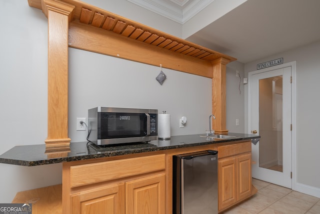 kitchen featuring refrigerator, decorative columns, sink, light tile patterned floors, and dark stone counters