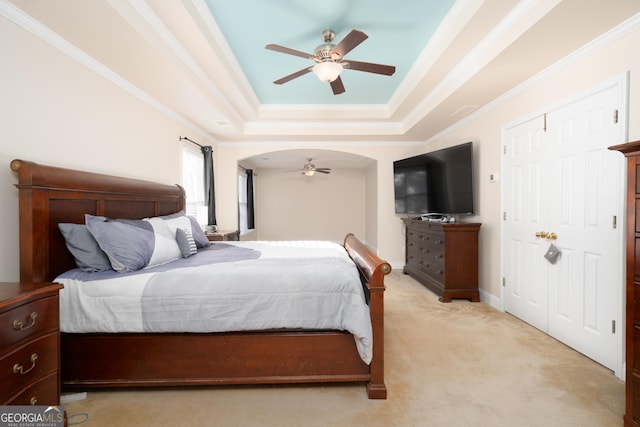 bedroom featuring ceiling fan, crown molding, a raised ceiling, and light carpet