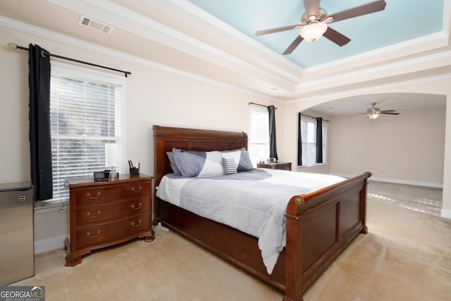 bedroom featuring ornamental molding, a raised ceiling, and light colored carpet