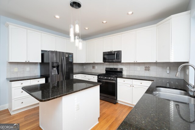 kitchen featuring appliances with stainless steel finishes, sink, a center island, white cabinetry, and hanging light fixtures