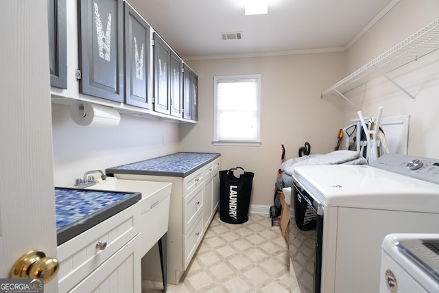 laundry room with washing machine and dryer, cabinets, and ornamental molding