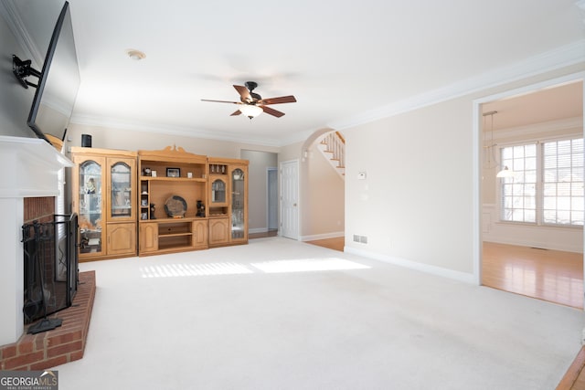 carpeted living room featuring a fireplace, ornamental molding, and ceiling fan