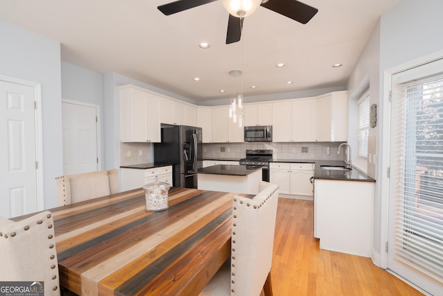 kitchen with sink, a center island, pendant lighting, stainless steel appliances, and white cabinets