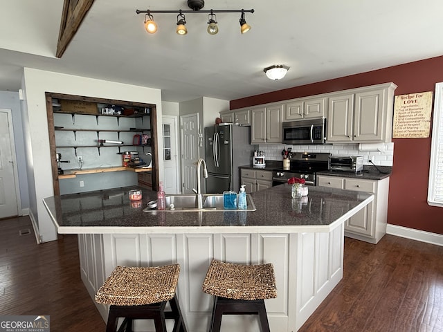 kitchen with appliances with stainless steel finishes, a breakfast bar, sink, backsplash, and dark hardwood / wood-style flooring