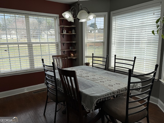 dining space with dark hardwood / wood-style flooring and an inviting chandelier