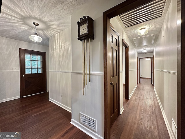 corridor featuring a textured ceiling and dark hardwood / wood-style flooring