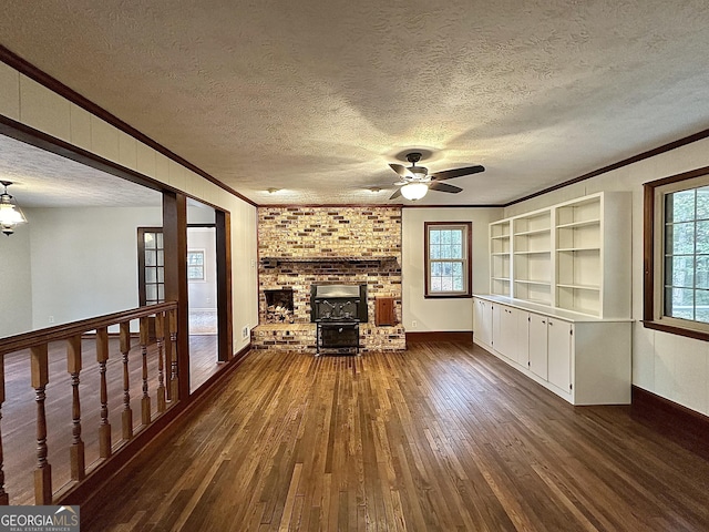 unfurnished living room with dark wood-type flooring, a textured ceiling, a wood stove, ornamental molding, and ceiling fan