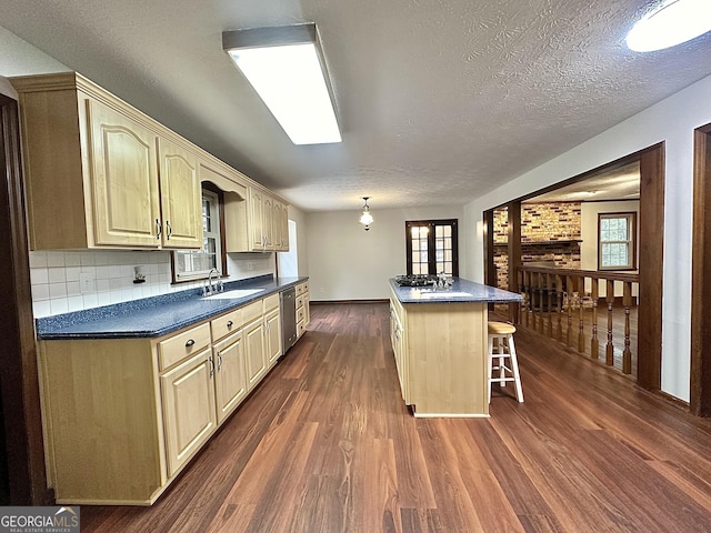 kitchen with sink, a kitchen island, a kitchen bar, dark hardwood / wood-style flooring, and stainless steel dishwasher