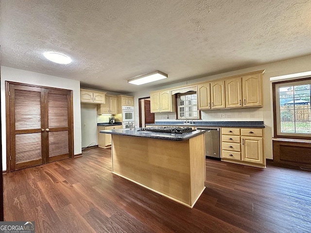 kitchen featuring dark wood-type flooring, stainless steel dishwasher, a kitchen island, and light brown cabinets