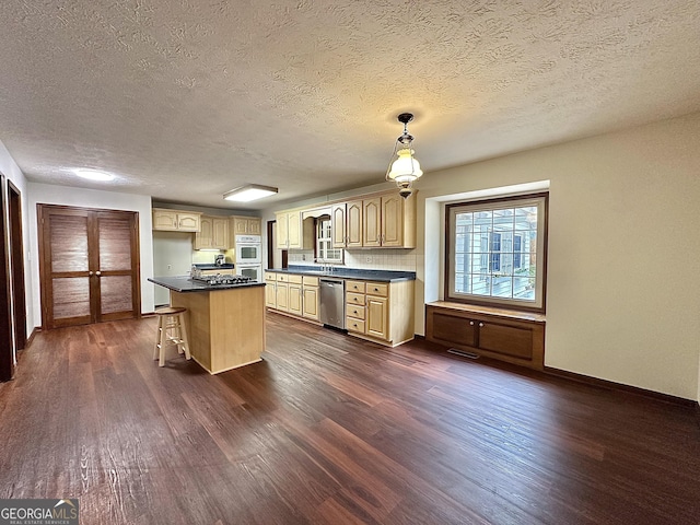 kitchen featuring appliances with stainless steel finishes, dark hardwood / wood-style floors, a center island, and hanging light fixtures