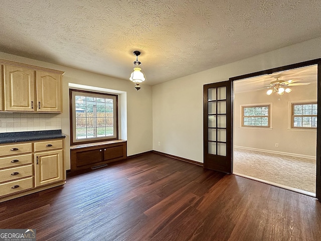 unfurnished dining area with ceiling fan, dark hardwood / wood-style floors, and a textured ceiling