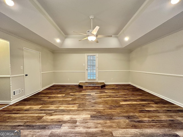 empty room featuring a raised ceiling, crown molding, dark hardwood / wood-style floors, and ceiling fan