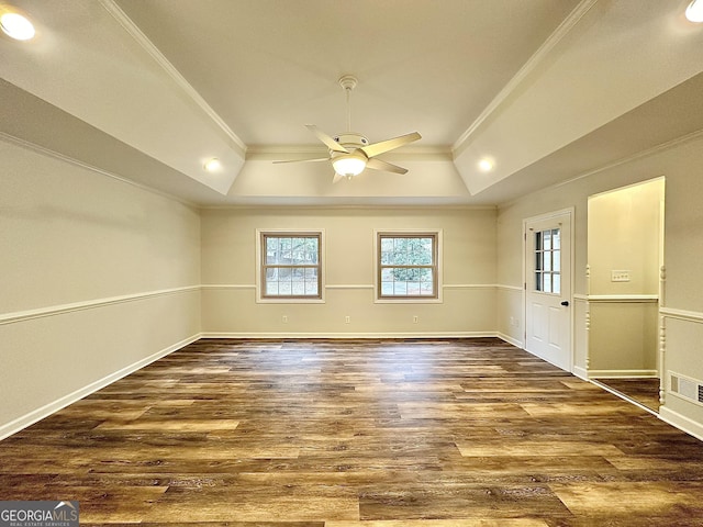 unfurnished room featuring dark wood-type flooring, ceiling fan, ornamental molding, and a raised ceiling